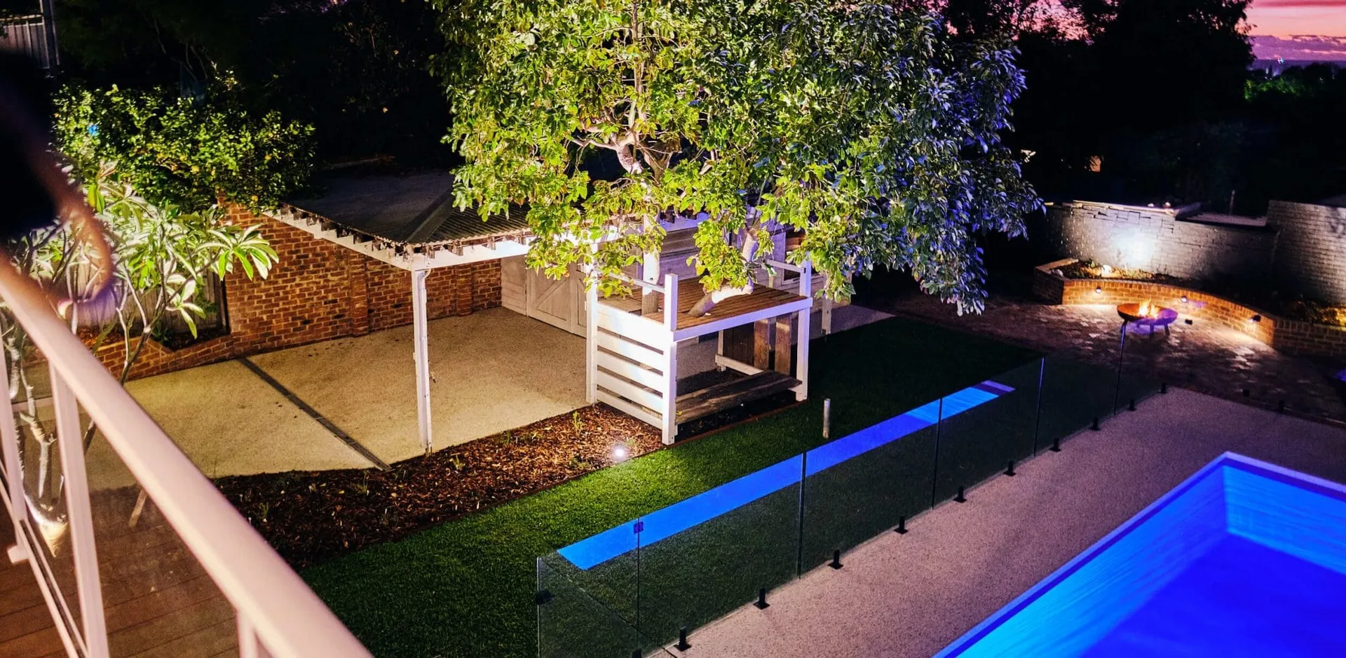 Beaconsfield Perth backyard makeover at night with lit pool, alfresco and feature garden lighting.