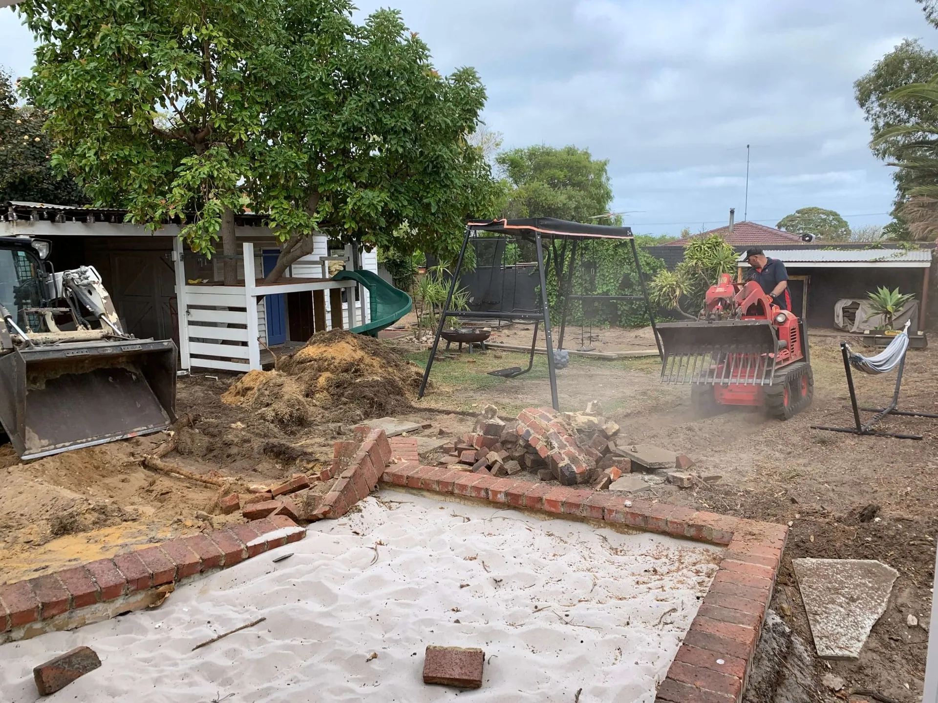 Breaking ground on the Beaconsfield Perth backyard makeover with excavator removing old features.