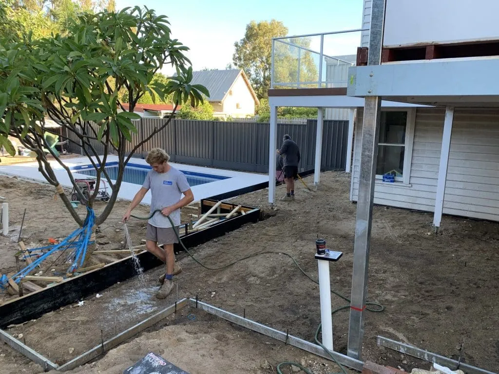 Watering freshly prepared soil during the Beaconsfield Perth backyard landscape construction.