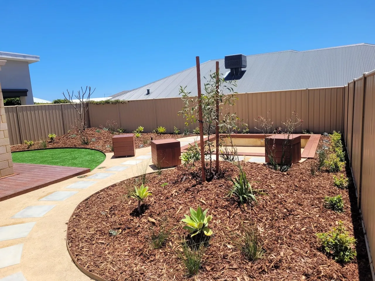 Completed Beeliar Perth backyard landscape design with firepit, mounded garden beds and seating.